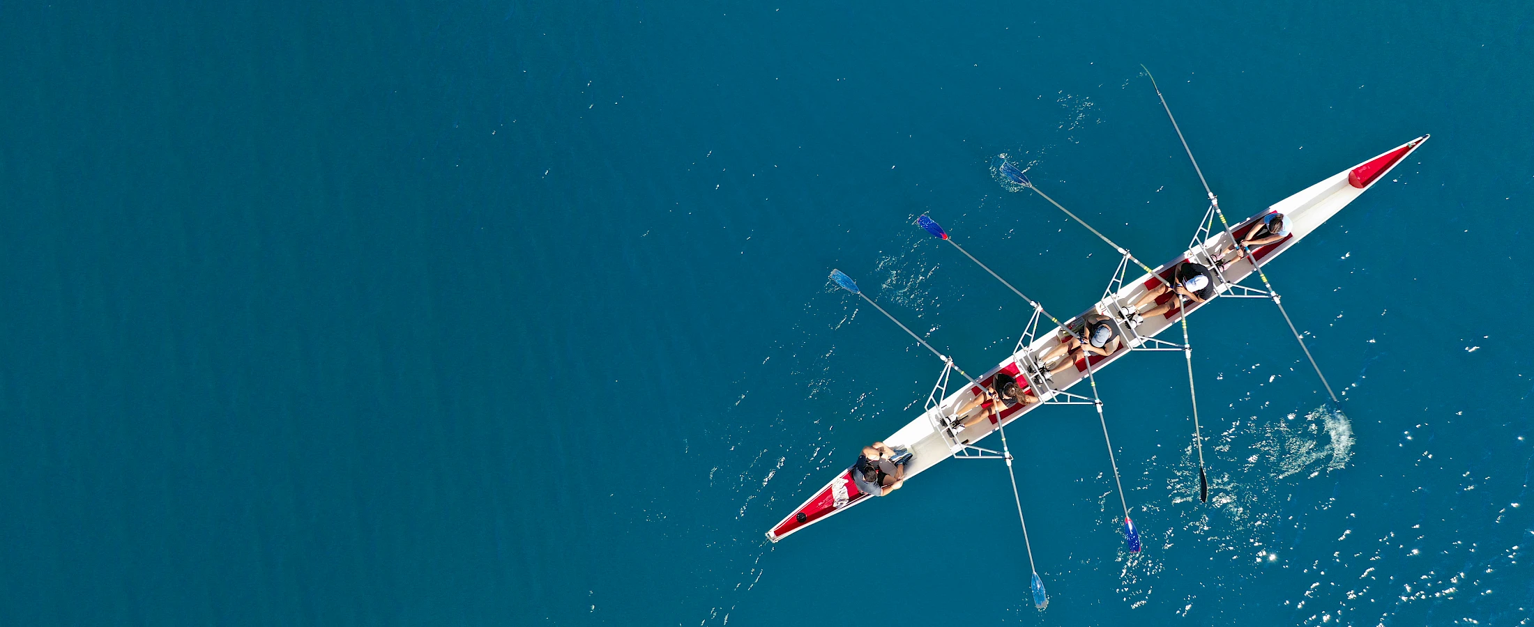 A rowing crew moving together across turquoise water