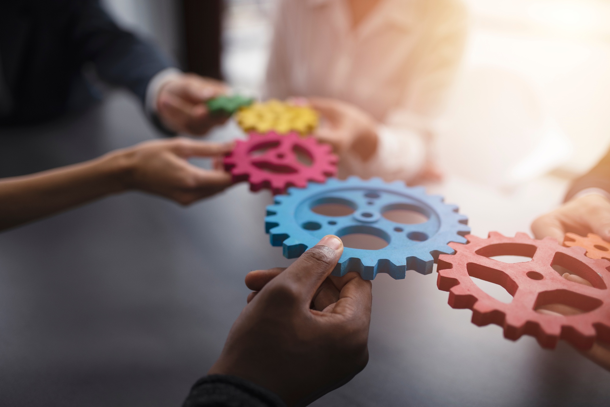 People bringing colourful interlocking gears together